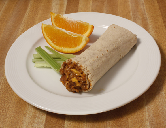 Plate of foodservice Posada Mexican Bean and Cheese Butrrito with Celery and Orange Slices in a school setting
