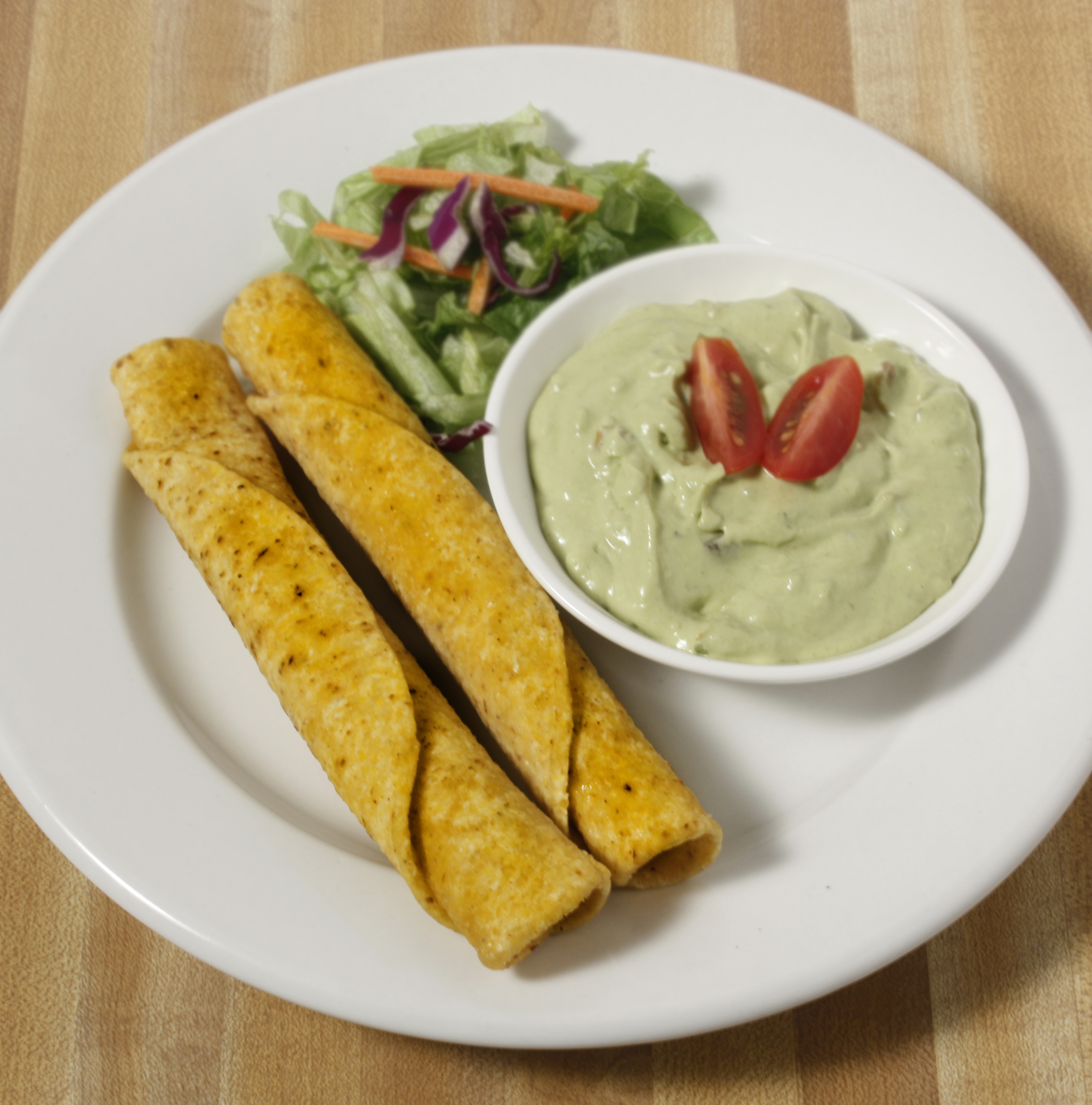 Plate of foodservice Posada Mexican Taquitos with Salad and Dipping Sauce in a school setting