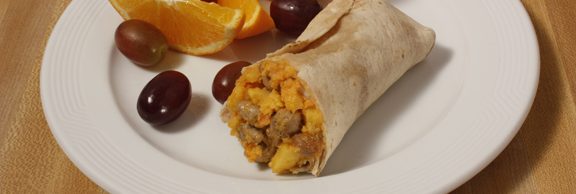 Plate of foodservice Posada Mexican Egg, Sausage and Cheese Breakfast Burrito with Fruit in a school setting