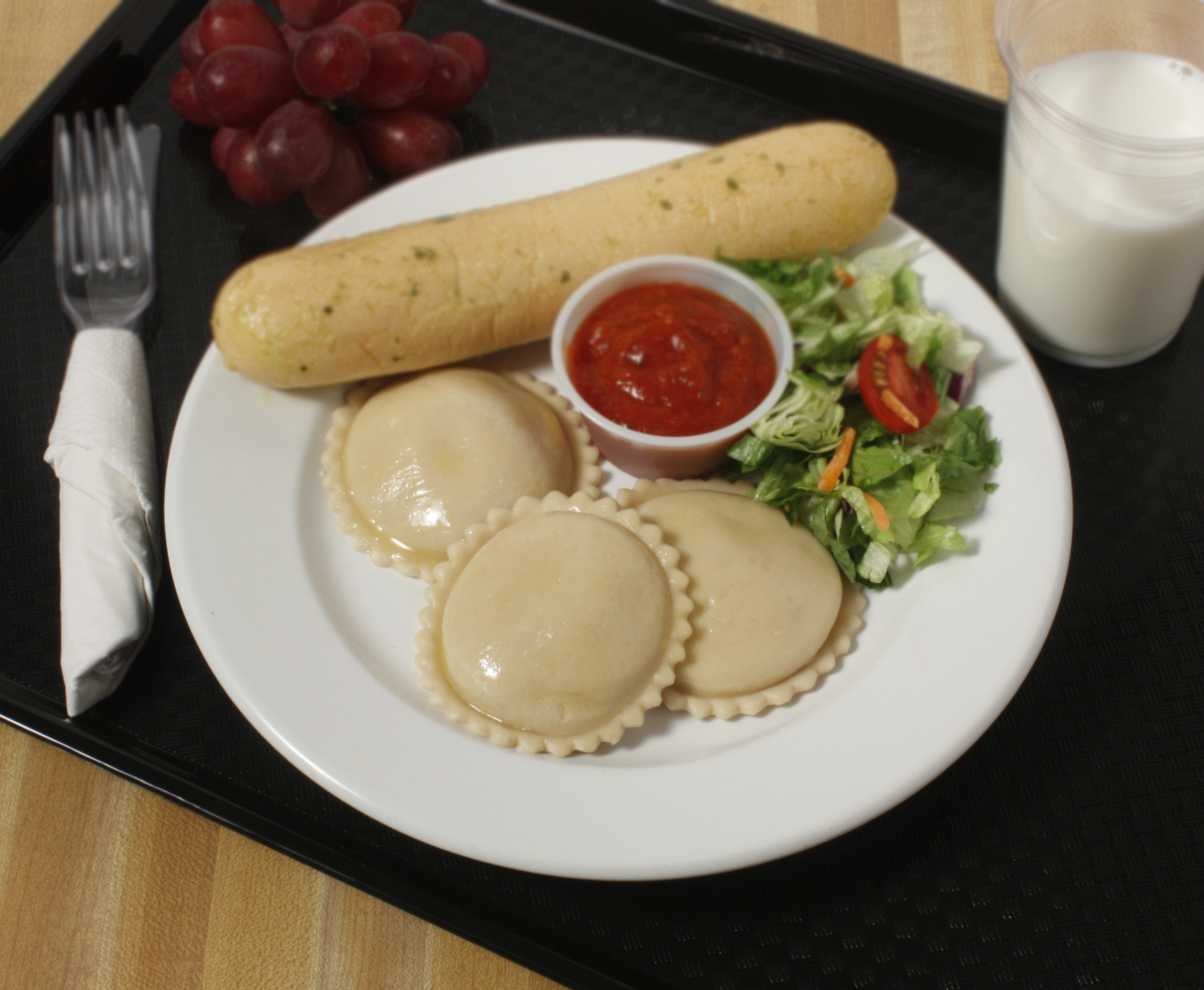 Plate of foodservice Bernardi Italian Ravioli with Salad and a Breadstick in a school setting